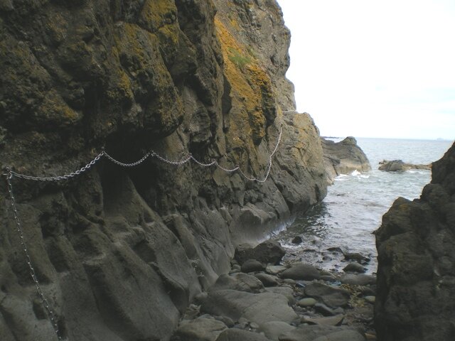 Chains fixed across the columned volcanic rock face at Kincraig Point, above the boulder shore