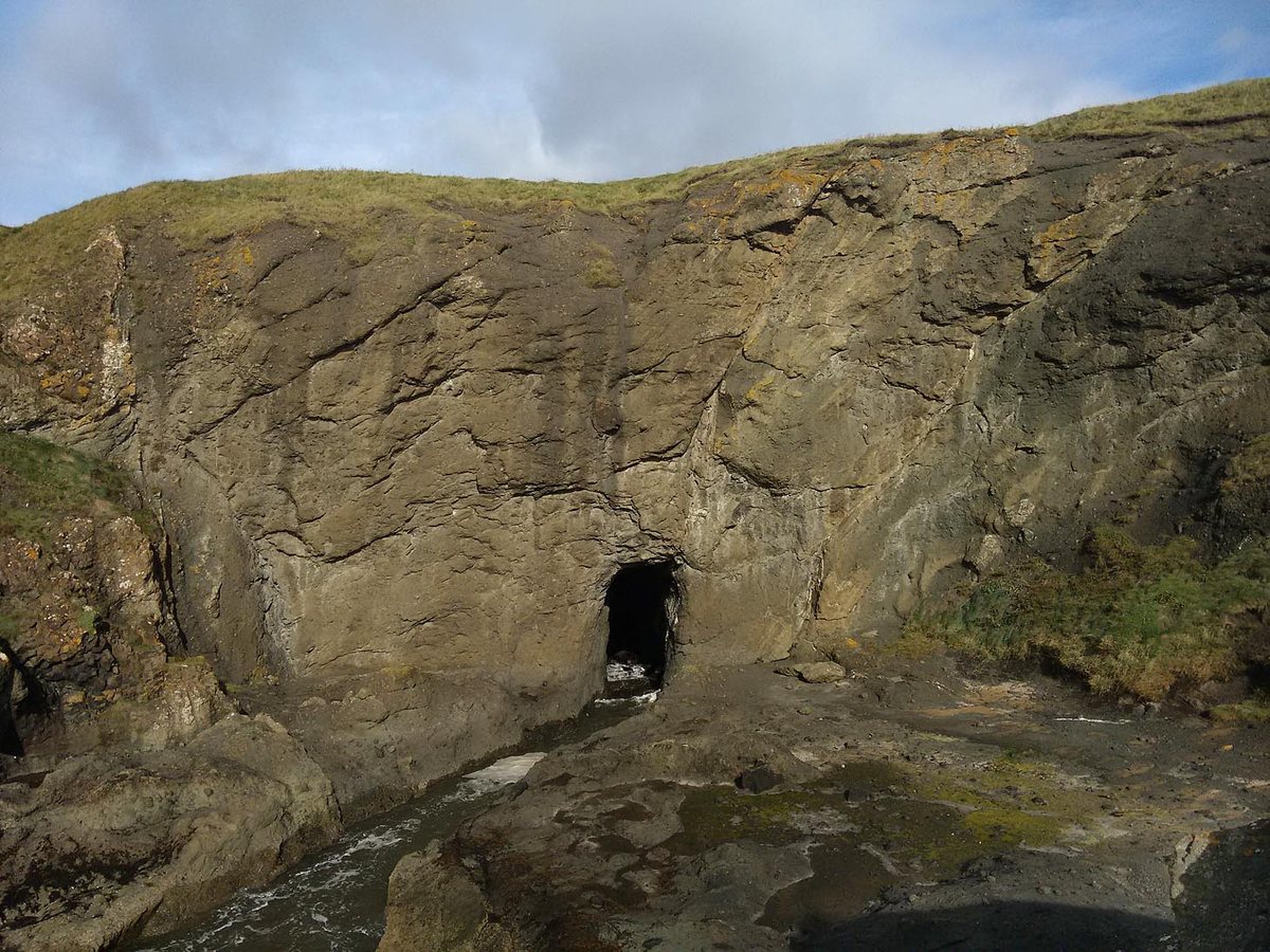 The dark mouth of the Devil's Cave in the sandstone cliff at Kincraig Point