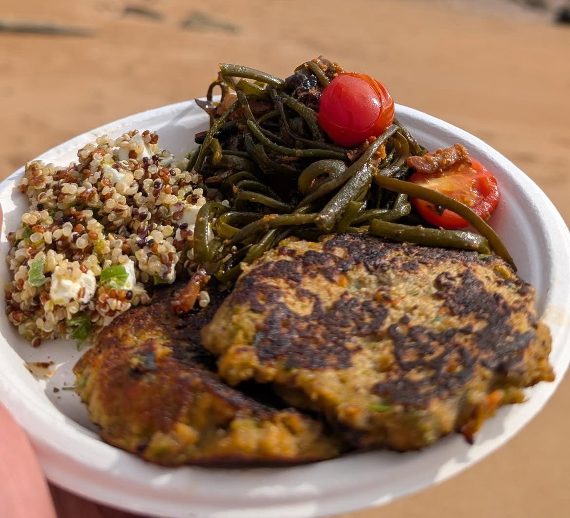 A plate of pesto sea spaghetti, mussel fritters and grains, eaten on the beach