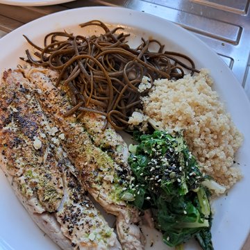 Grilled fish with sea spaghetti, quinoa and wilted greens on a plate